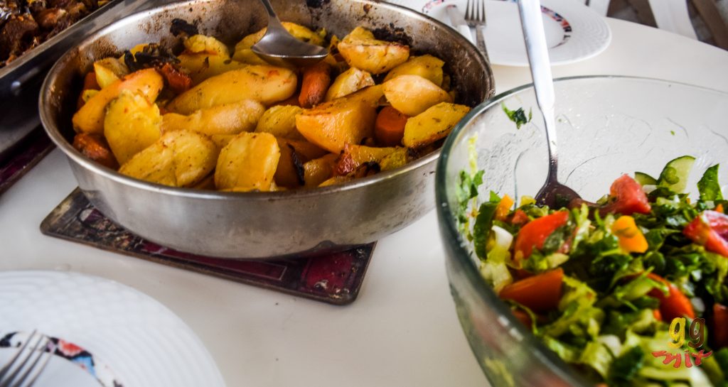 A TRAY OF ROAST POTATOES AND A BOWL OF GREEK SALAD