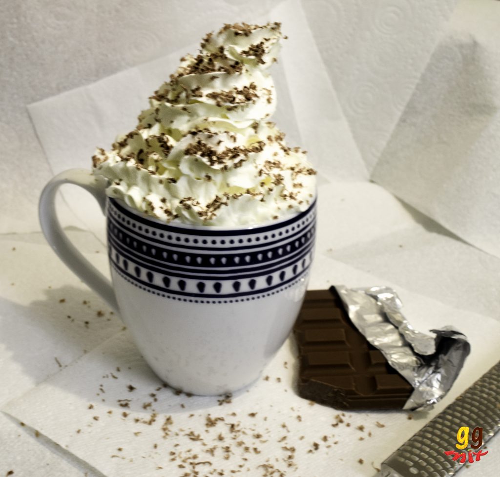 a mug of hot chocolate topped with whipped cream and chocolate shavings