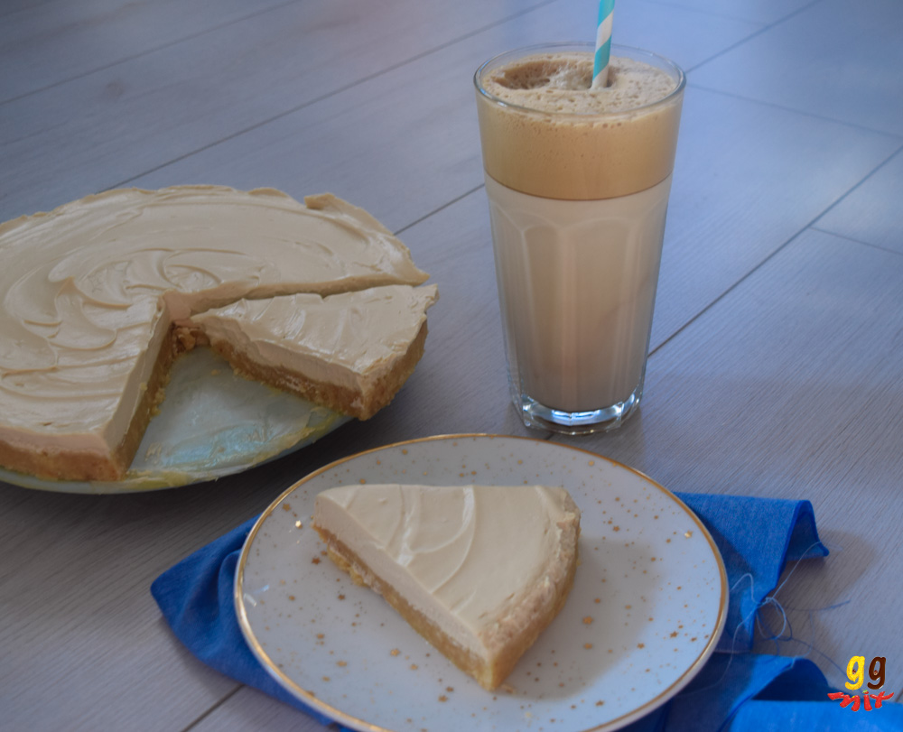 a greek frappe coffee cheesecake with 2 slices cut out and a glass of greek frappr coffee